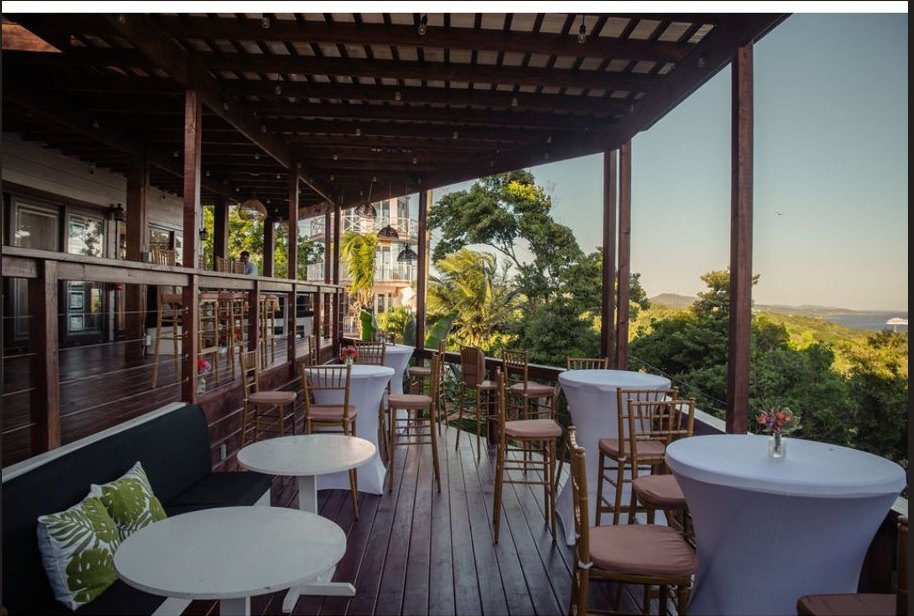 The Windward Terraces deck — pergola, cocktail tables, and ocean view at golden hour