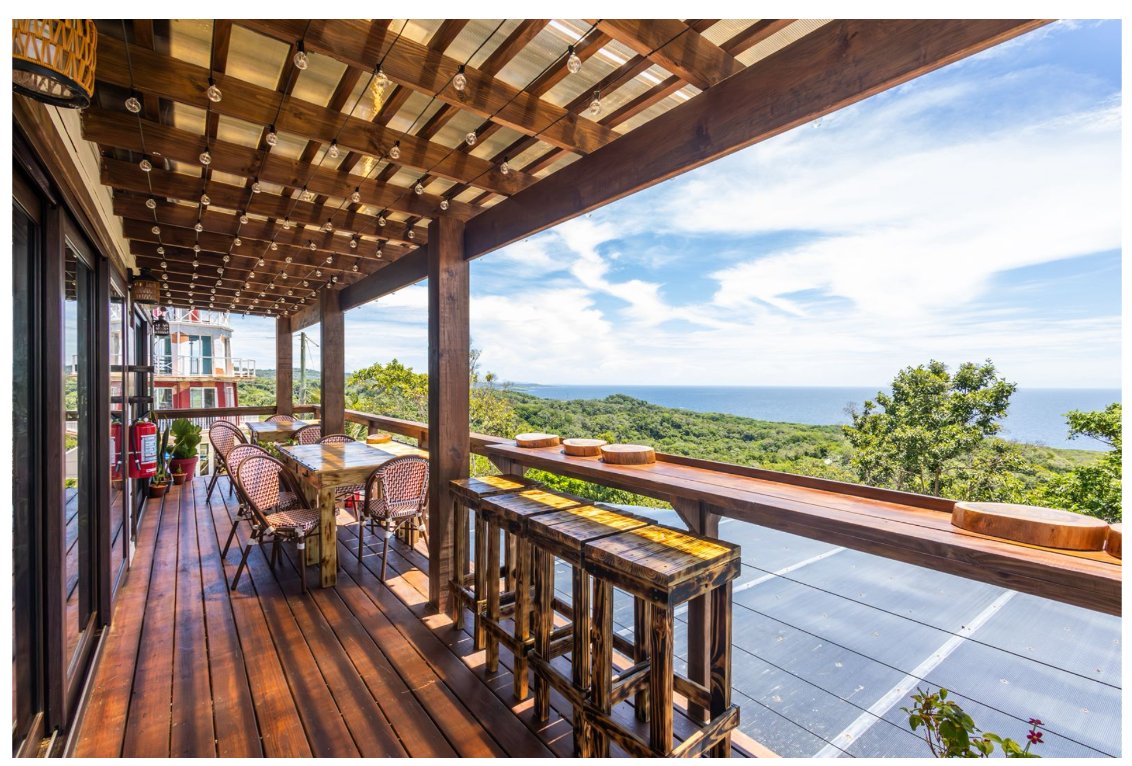 Covered deck terrace dining with string lights and ocean view at Windward Terraces